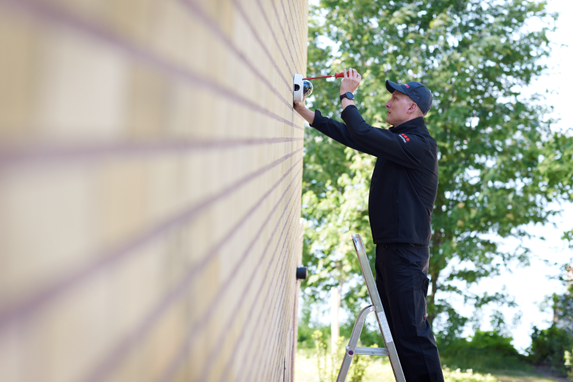 Man installing security cameras on wall