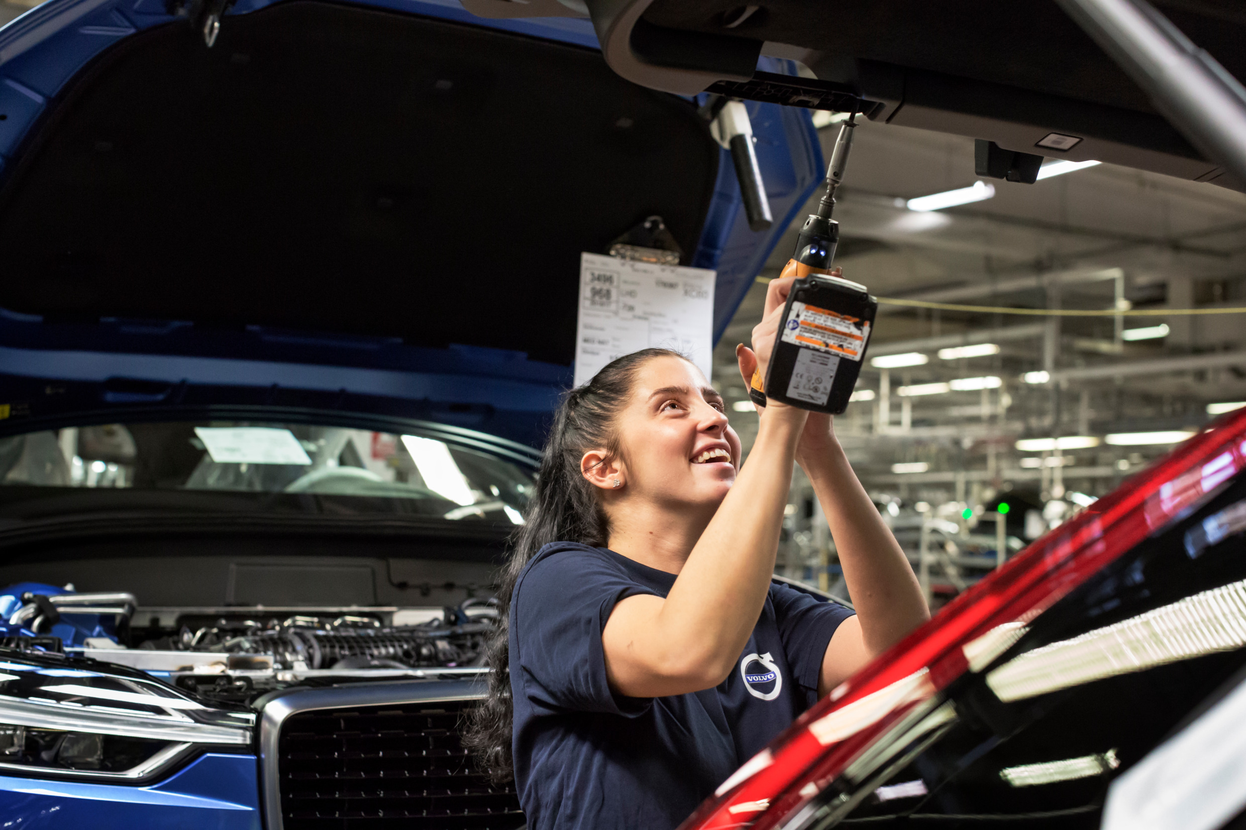 Woman working on car in industrial setting
